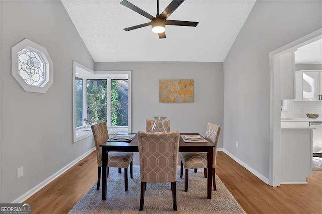 dining space with a textured ceiling, ceiling fan, vaulted ceiling, and hardwood / wood-style flooring