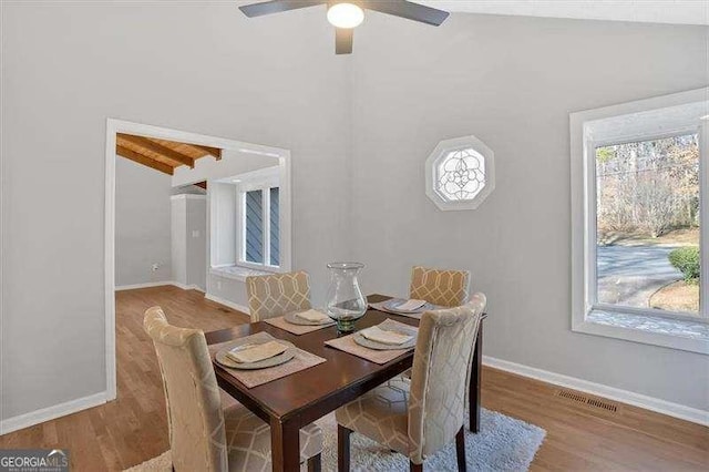 dining room with beam ceiling, light hardwood / wood-style flooring, and ceiling fan