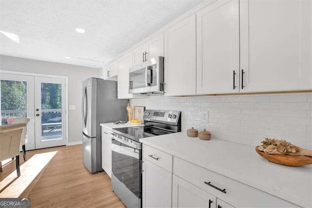 kitchen with french doors, white cabinets, light hardwood / wood-style flooring, a textured ceiling, and stainless steel appliances