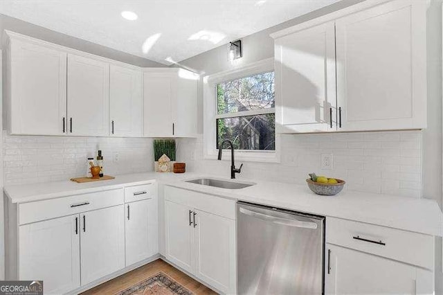 kitchen featuring tasteful backsplash, white cabinetry, dishwasher, and sink