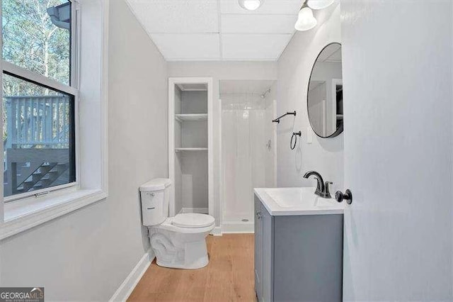 bathroom featuring wood-type flooring, vanity, toilet, and walk in shower