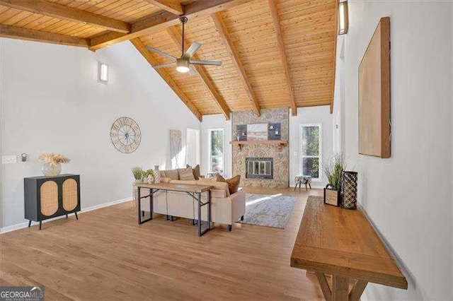 living room featuring beamed ceiling, a stone fireplace, and wooden ceiling