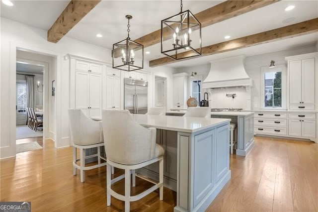 kitchen with white cabinets, a spacious island, premium range hood, and stainless steel appliances