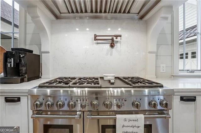 kitchen featuring light stone countertops, extractor fan, and range with two ovens