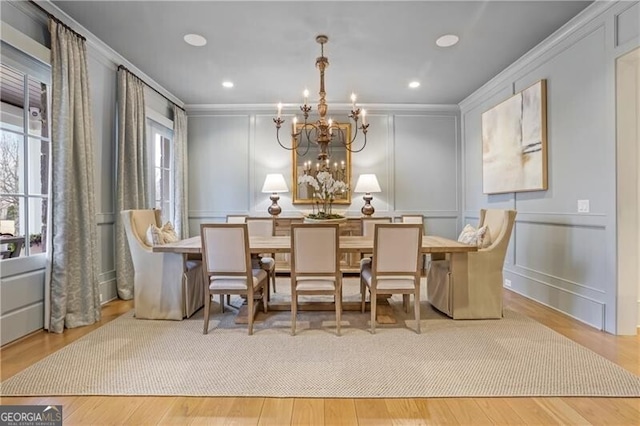 dining area with light hardwood / wood-style flooring, crown molding, and a notable chandelier