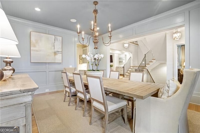 dining space featuring light hardwood / wood-style floors, ornamental molding, and a notable chandelier