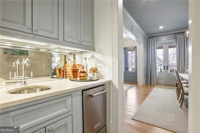 bar featuring gray cabinetry, french doors, sink, ornamental molding, and light hardwood / wood-style floors