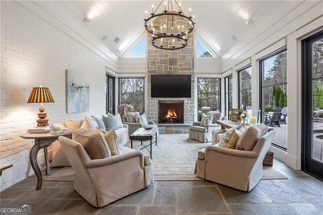 living room featuring high vaulted ceiling, a stone fireplace, a notable chandelier, wood ceiling, and brick wall