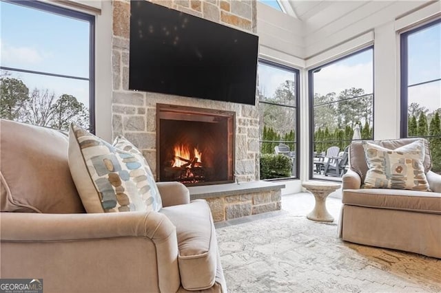 sunroom / solarium featuring a stone fireplace and vaulted ceiling