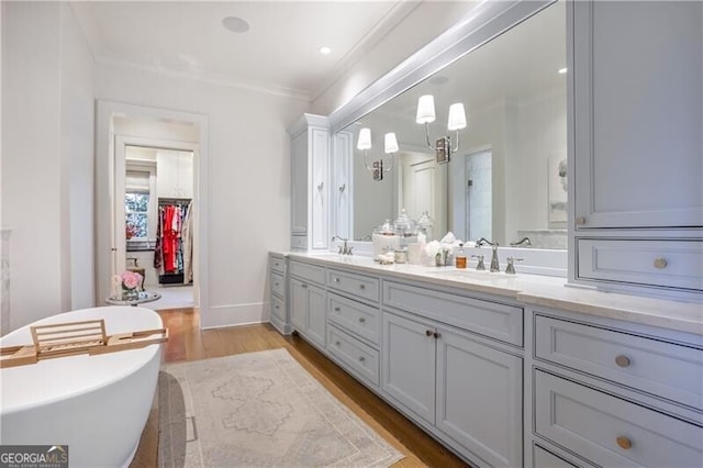 bathroom with a bathing tub, hardwood / wood-style floors, vanity, and crown molding