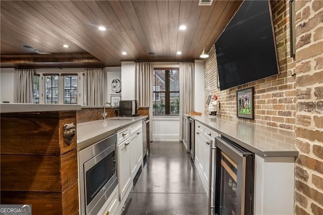 kitchen with stainless steel microwave, wooden ceiling, sink, white cabinetry, and beverage cooler