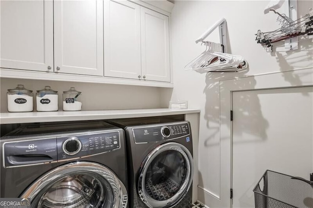 laundry room featuring washer and clothes dryer and cabinets