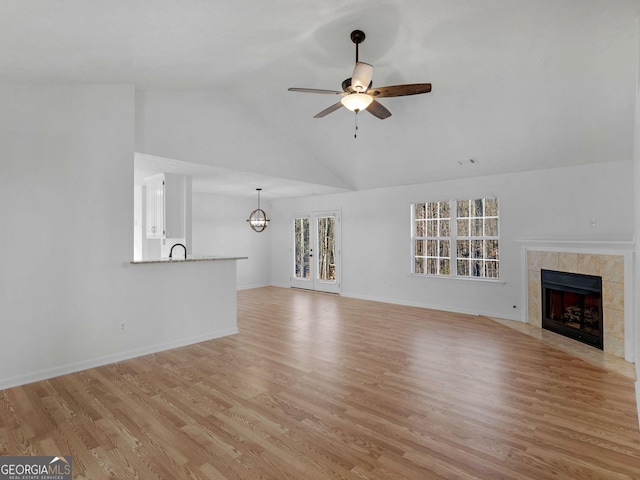 unfurnished living room featuring ceiling fan, light wood finished floors, vaulted ceiling, and a fireplace