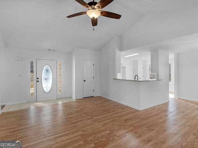 entrance foyer with ceiling fan, lofted ceiling, and light hardwood / wood-style flooring