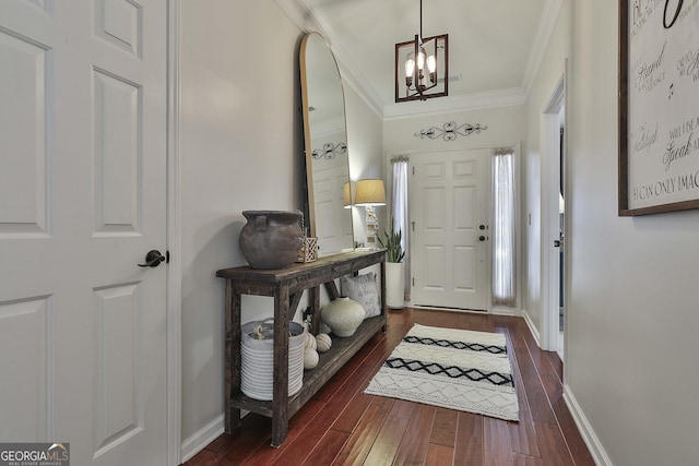 entrance foyer featuring a notable chandelier, ornamental molding, and dark wood-type flooring