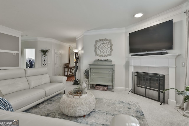 living room with independent washer and dryer, a tile fireplace, light carpet, and ornamental molding