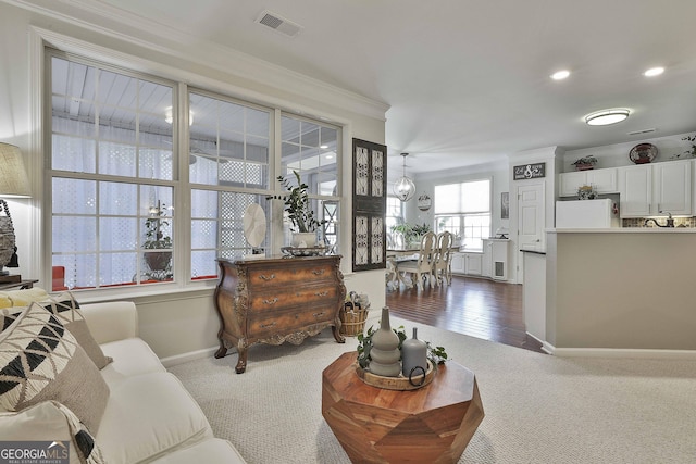 living room featuring crown molding, a chandelier, and dark colored carpet