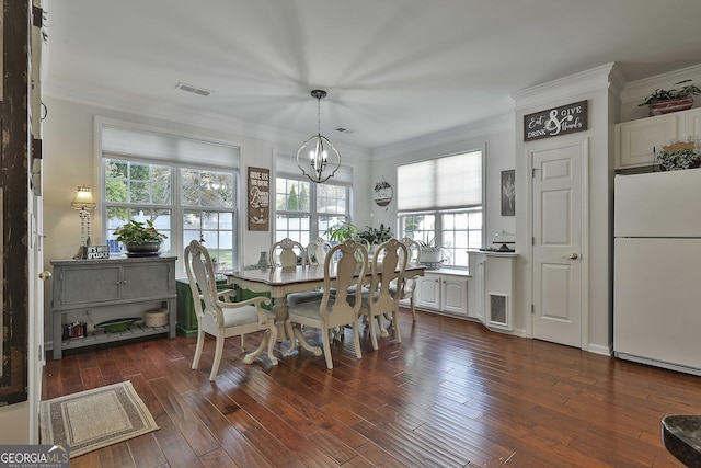 dining area with dark hardwood / wood-style flooring, crown molding, and a chandelier