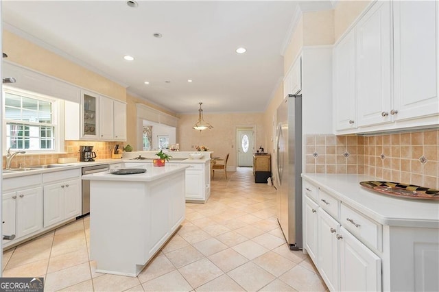 kitchen with kitchen peninsula, stainless steel appliances, sink, a kitchen island, and hanging light fixtures