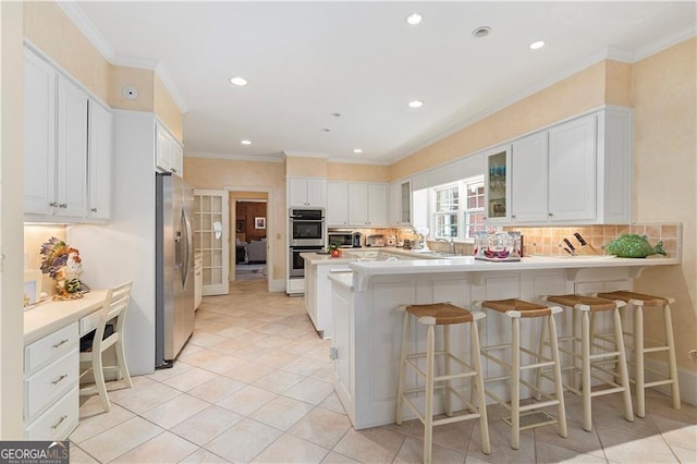 1120 Heards Ferry Rd, Sandy Springs, GA 30328 - kitchen featuring stainless steel appliances, a peninsula, glass insert cabinets, white cabinets, and a breakfast bar