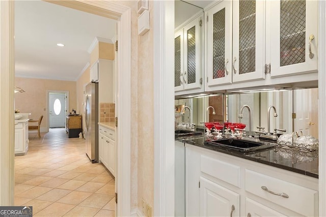 bar featuring stainless steel fridge, light tile patterned floors, white cabinetry, and ornamental molding