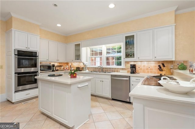 1120 Heards Ferry Rd, Sandy Springs, GA 30328 - kitchen featuring appliances with stainless steel finishes, tasteful backsplash, white cabinets, a center island, and crown molding