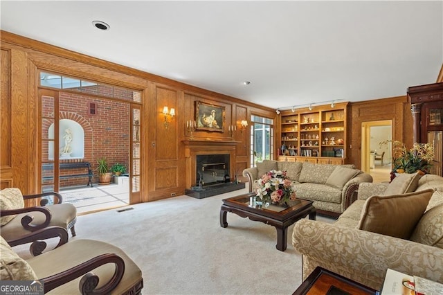 carpeted living room featuring built in shelves and wood walls