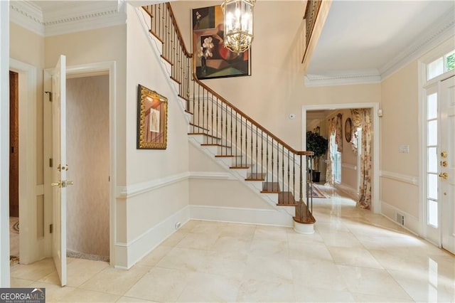 foyer entrance with crown molding and a chandelier