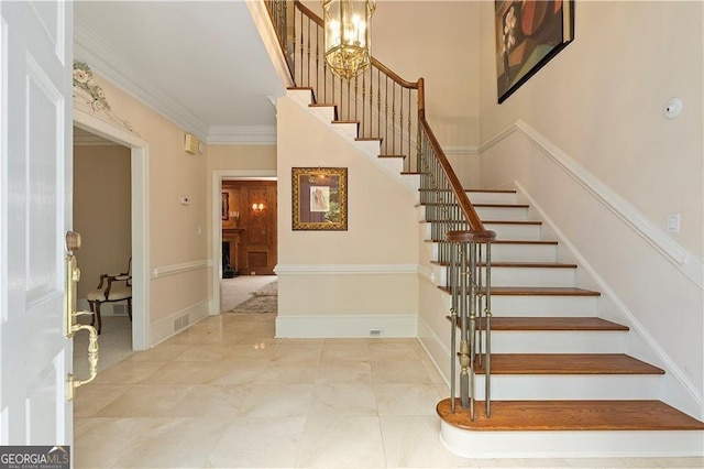 stairway with ornamental molding and an inviting chandelier