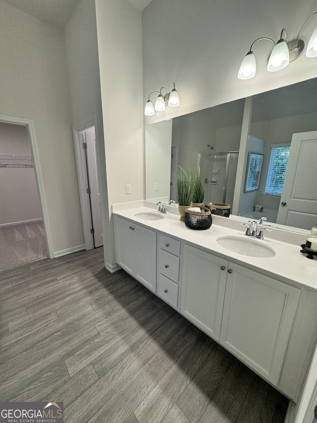 bathroom featuring vanity, a shower with shower door, hardwood / wood-style floors, and a high ceiling