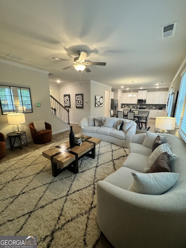 living room featuring ornamental molding, light wood-type flooring, a wealth of natural light, and ceiling fan