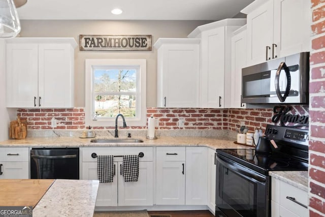 kitchen featuring black appliances, white cabinets, light stone countertops, and sink