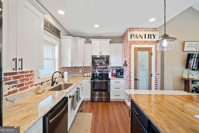 kitchen featuring pendant lighting, sink, appliances with stainless steel finishes, white cabinetry, and butcher block counters