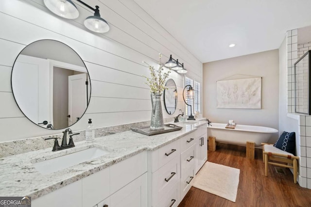 bathroom featuring a washtub, hardwood / wood-style floors, and vanity