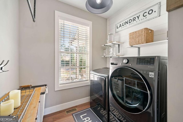 washroom featuring wood-type flooring, separate washer and dryer, and a wealth of natural light