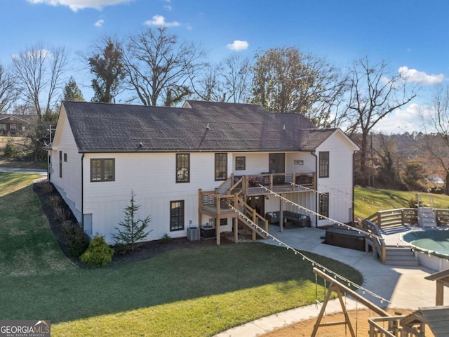 rear view of house with a lawn, a wooden deck, and a patio