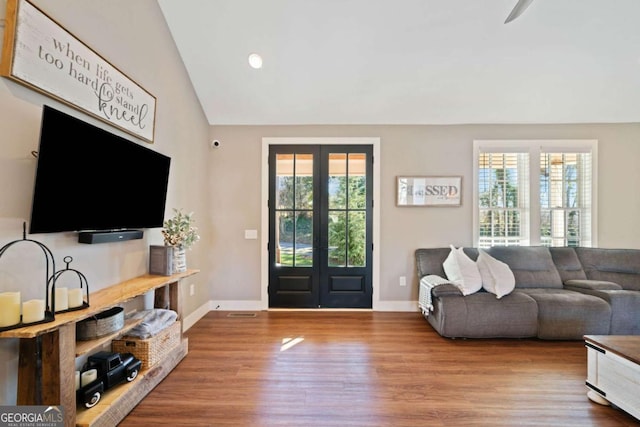 living room featuring plenty of natural light, vaulted ceiling, wood-type flooring, and french doors