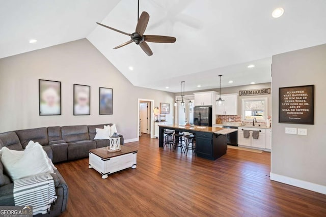 living room with ceiling fan, sink, high vaulted ceiling, and dark wood-type flooring