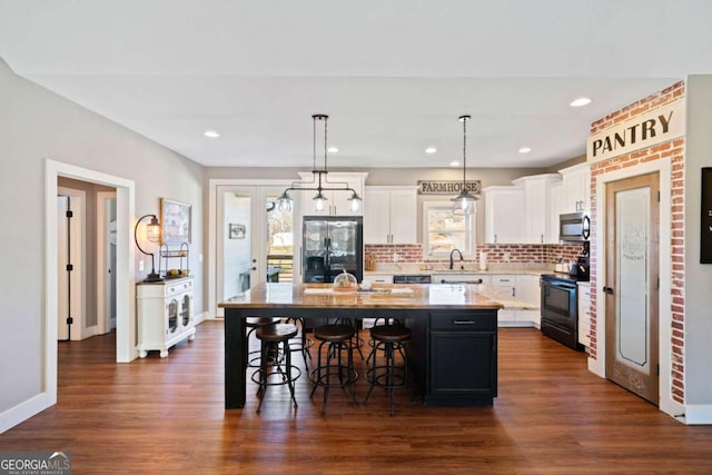 kitchen featuring pendant lighting, decorative backsplash, black / electric stove, refrigerator with ice dispenser, and a kitchen island