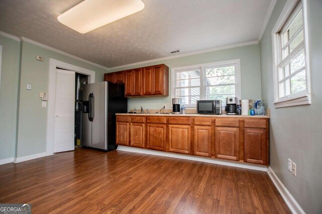 kitchen featuring crown molding, stainless steel fridge with ice dispenser, a textured ceiling, and dark wood-type flooring