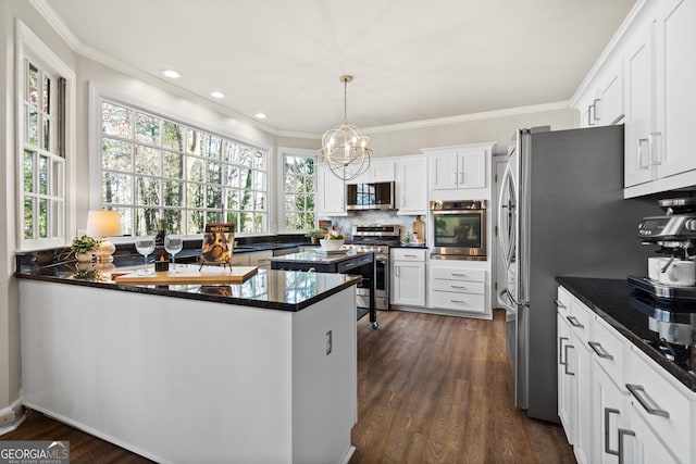 kitchen with stainless steel appliances, white cabinetry, kitchen peninsula, and hanging light fixtures