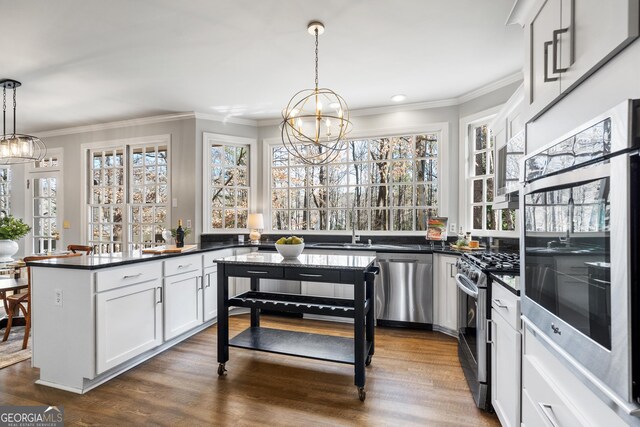 kitchen featuring white cabinets, dark stone countertops, stainless steel appliances, sink, and an inviting chandelier