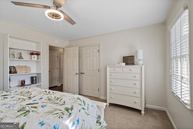 carpeted bedroom with a closet, ceiling fan, and ornamental molding