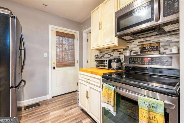 kitchen with decorative backsplash, appliances with stainless steel finishes, light hardwood / wood-style flooring, and butcher block counters