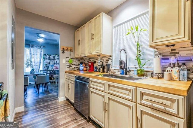 kitchen with sink, black dishwasher, butcher block countertops, cream cabinetry, and hardwood / wood-style flooring