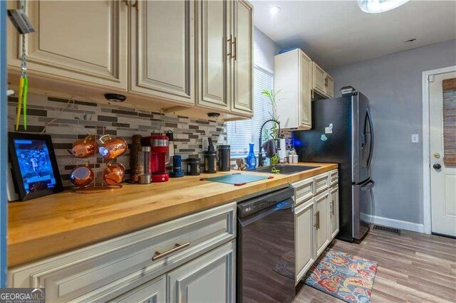 kitchen with tasteful backsplash, sink, cream cabinetry, dishwasher, and butcher block countertops