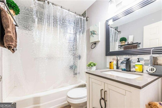 full bathroom featuring backsplash, shower / bath combo with shower curtain, vanity, and toilet