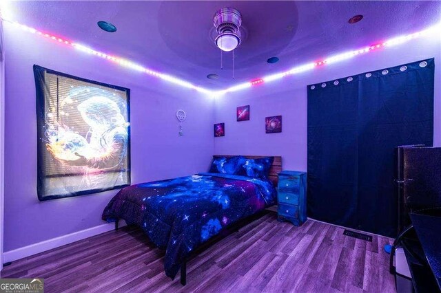 bedroom with wood-type flooring, a raised ceiling, and ceiling fan