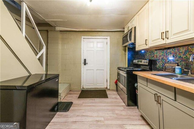 kitchen featuring butcher block countertops, light hardwood / wood-style floors, sink, and appliances with stainless steel finishes