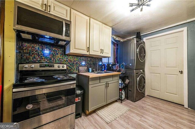 kitchen featuring light hardwood / wood-style flooring, decorative backsplash, appliances with stainless steel finishes, butcher block countertops, and stacked washer / drying machine